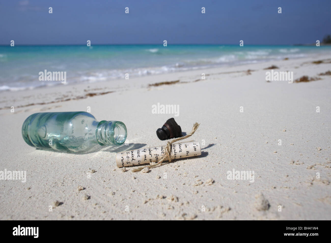 Eine Nachricht und eine Flasche auf dem Sand auf einem einsamen tropischen Strand Stockfoto