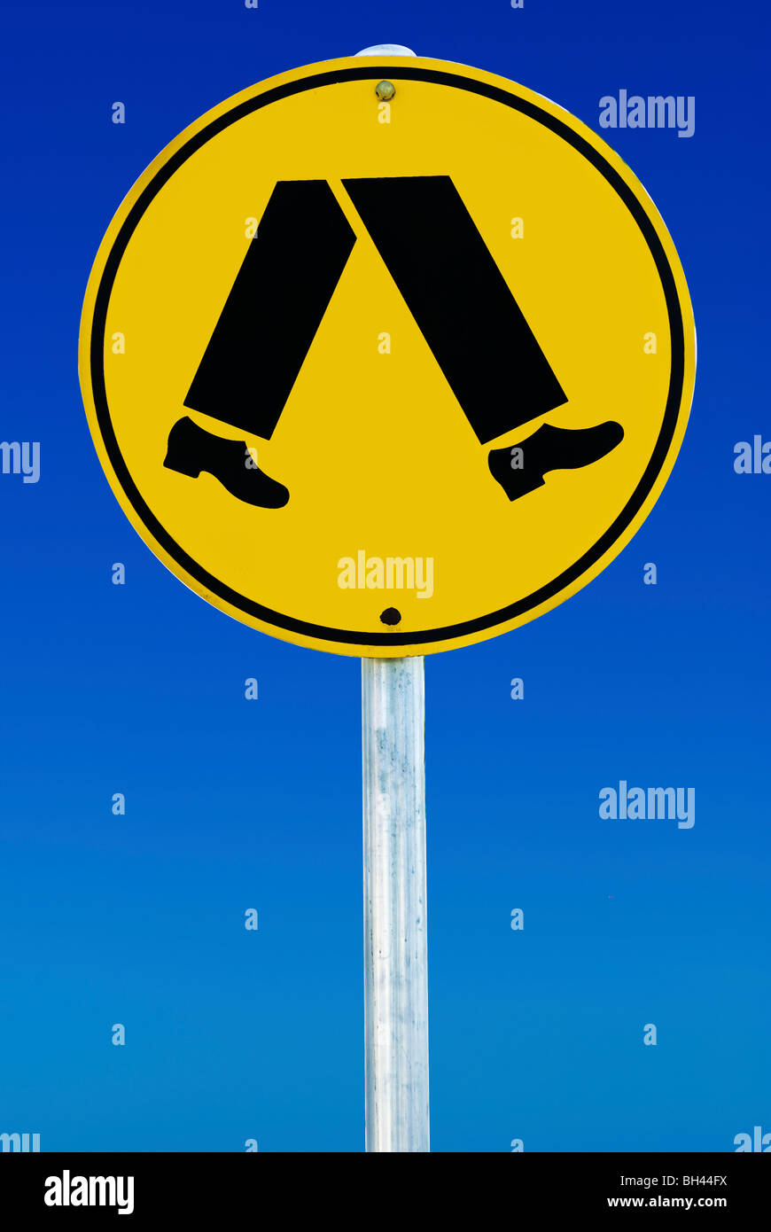 Ein Fußgängerüberweg Zeichen, bestehend aus ein paar Beine in einem Kreis auf einem blauen Gradienten Himmel isoliert. Stockfoto