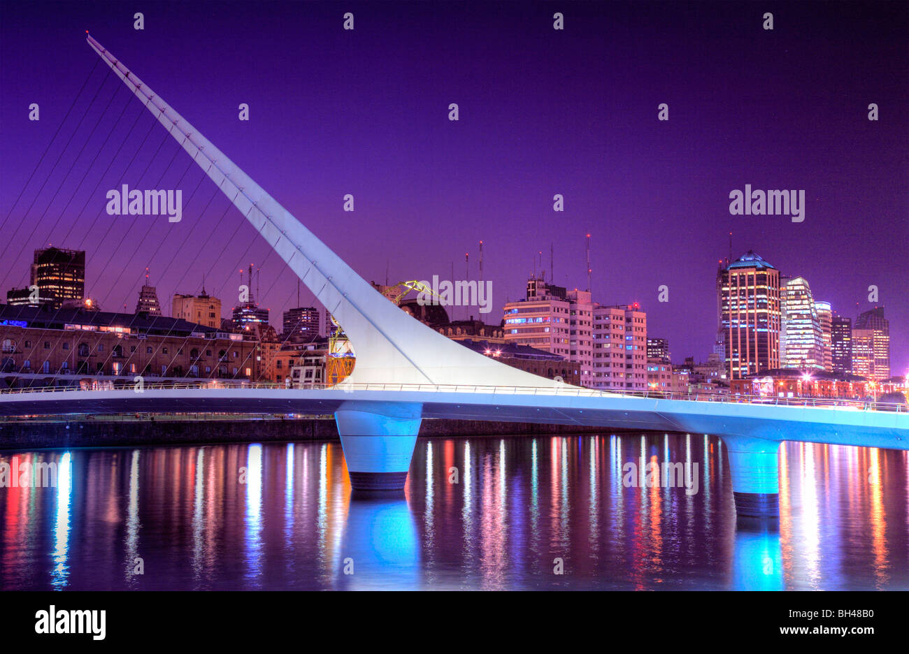 Brücke der Frau Sicht in der Dämmerung, mit Stadtsilhouette im Hintergrund und Wasser Reflexionen. Puerto Madero, Buenos Aires Stockfoto