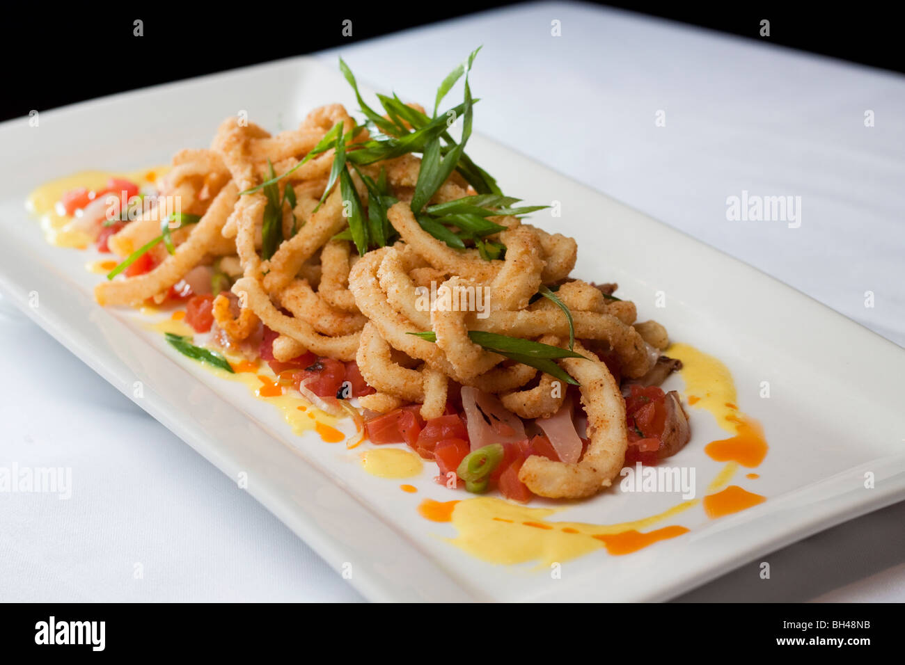 Ein Fried Calamari Vorspeise von einem Gourmet-Restaurant serviert mit Salsa und bunten Saucen Stockfoto