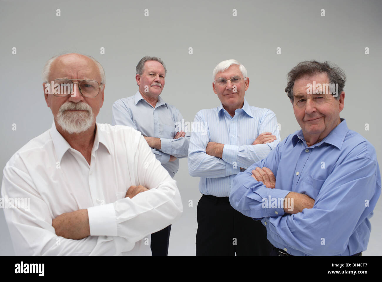 Vier leitende Geschäftsleute stehen mit Armen gefaltet, Lächeln Stockfoto