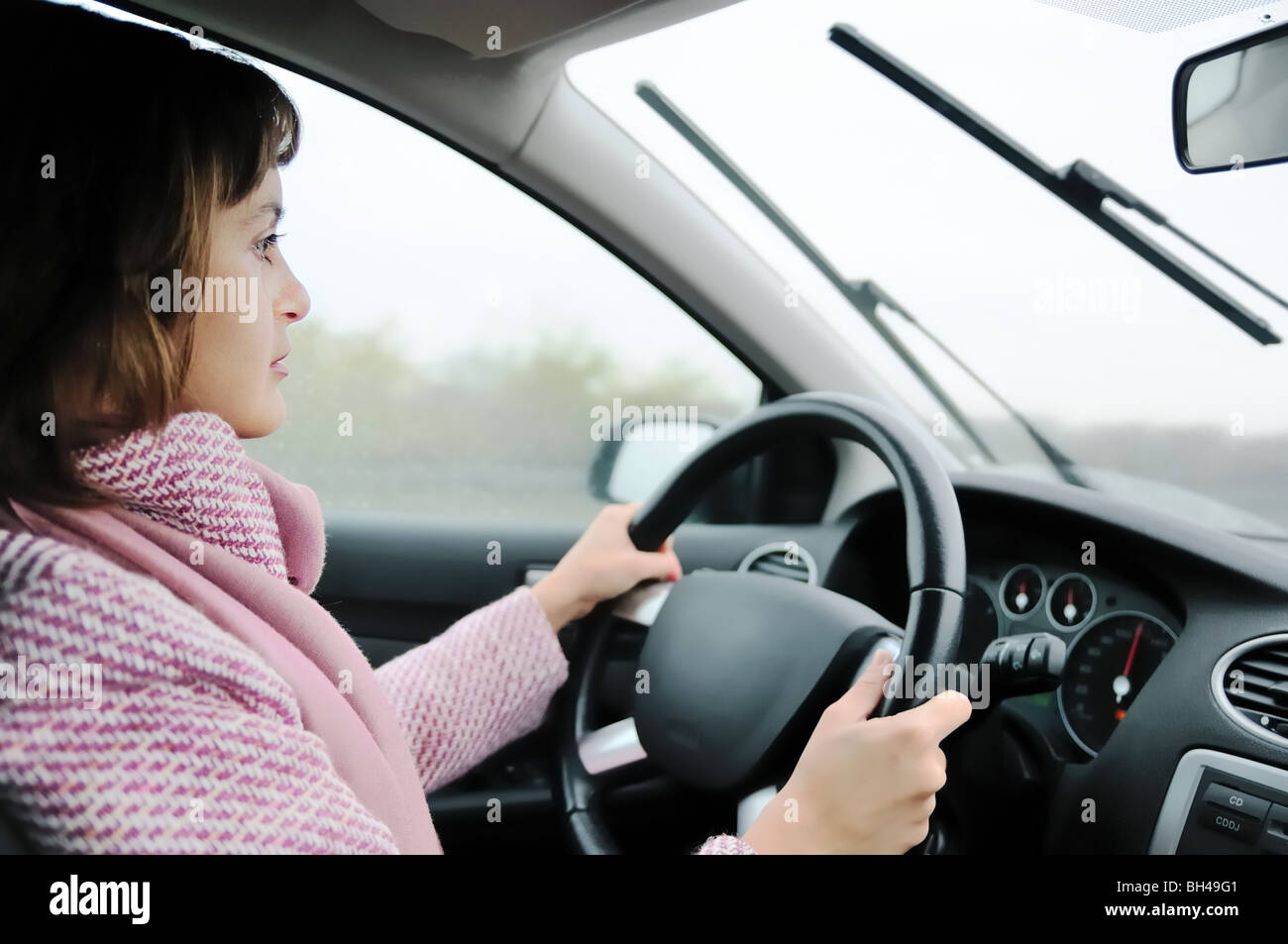 Junge Geschäftsfrau Autofahren im Regen (Schwerpunkt Gesicht) Stockfoto