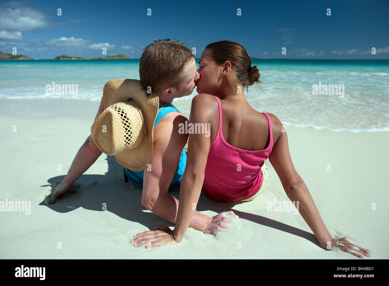 Junges Paar sitzt auf einem einsamen tropischen Strand, küssen Stockfoto