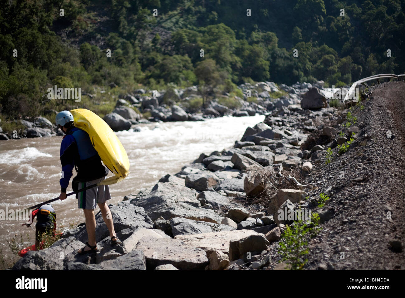 Eine weibliche Kajakfahrer trägt eine Kajak auf der Put-in auf einem Fluss. Stockfoto