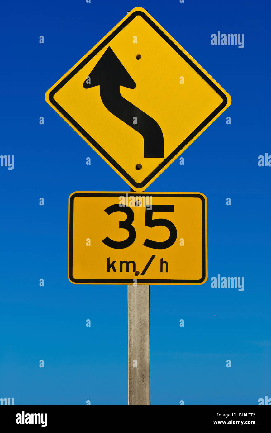 Ein Schild zeigt eine Kurve mit einer Reccomened Geschwindigkeit von 35km/h. isoliert auf einem abgestuften blauen Hintergrund. Stockfoto