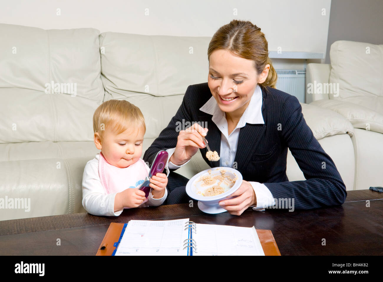 Geschäftsfrau mit Tagebuch, füttern ihr Baby girl Stockfoto