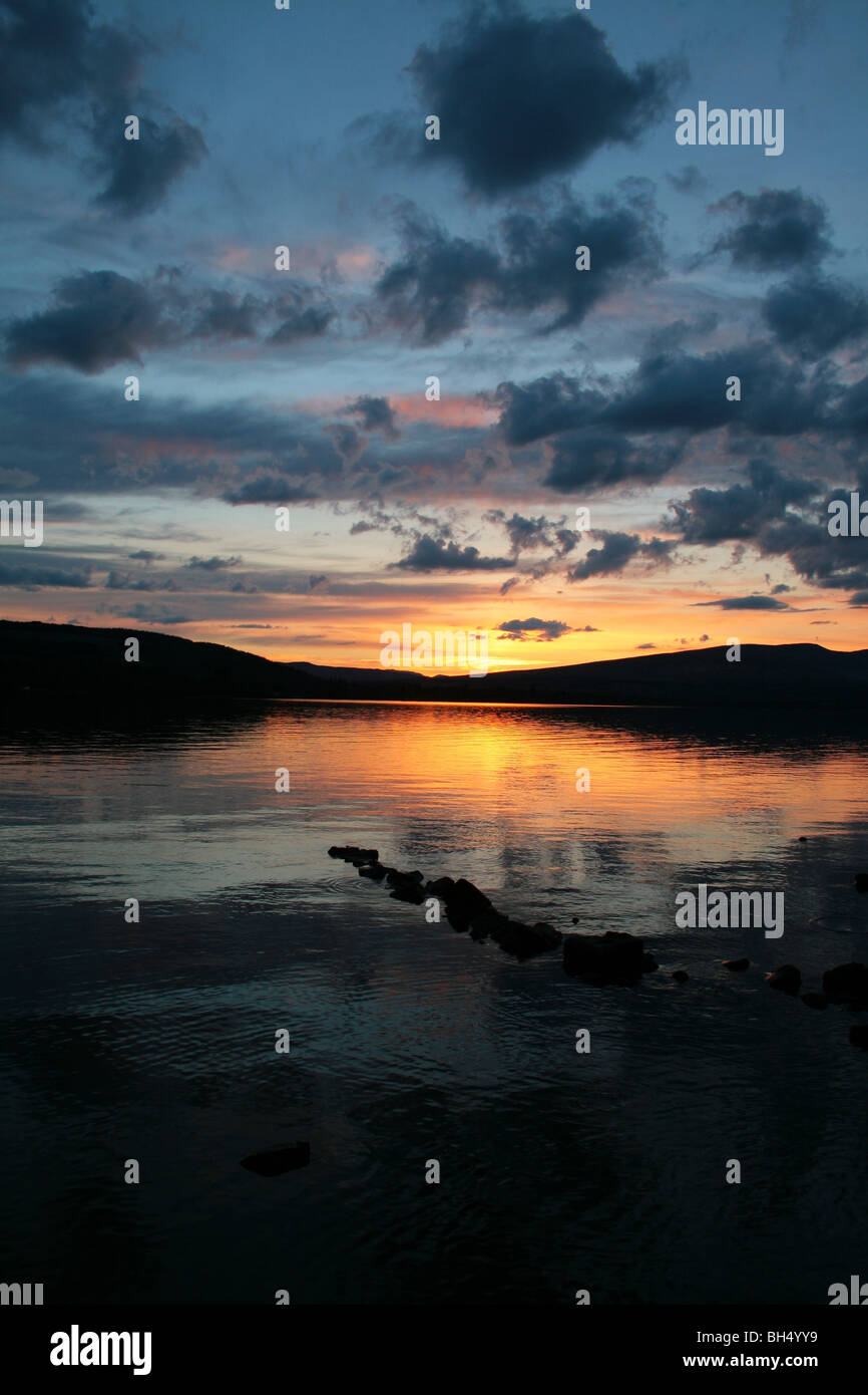 Die Sonne über einem felsigen Ufer von Loch Lomond. Stockfoto