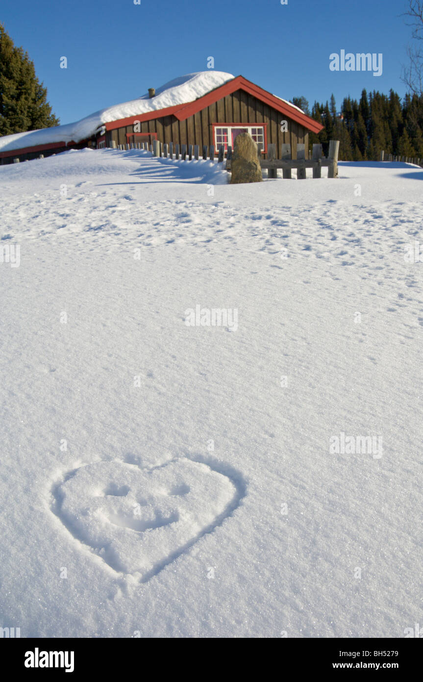 Ferienchalet mit Schnee und einen herzförmigen Smiley in den Schnee gezeichnet. Stockfoto