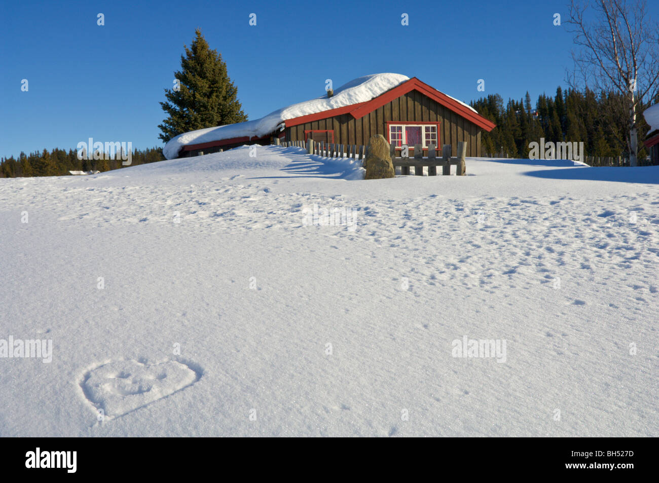 Ferienchalet mit Schnee und einen herzförmigen Smiley in den Schnee gezeichnet. Stockfoto