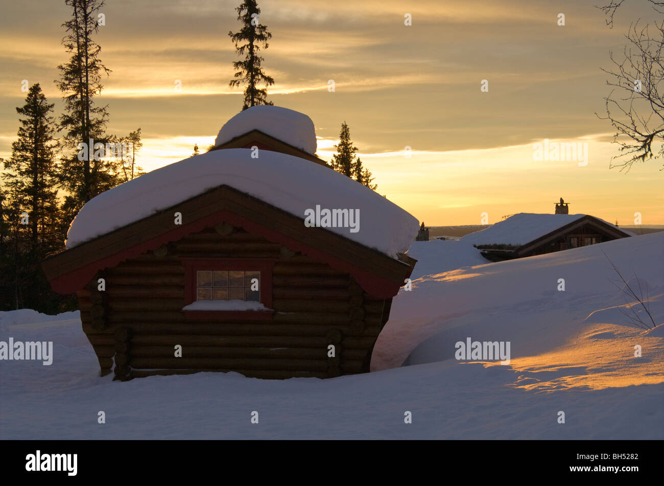 Ferienhäuser in verschneiter Landschaft bei Sonnenuntergang. Stockfoto