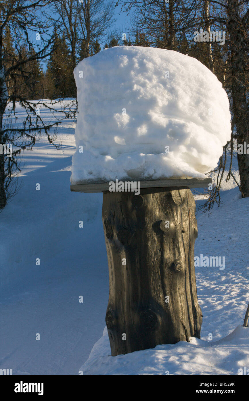 Rustikale Säule im Schnee mit Stapel der Schnee an der Spitze. Stockfoto