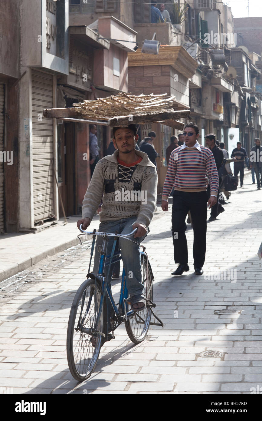 junger Mann mit Fahrrad tragen Paletten auf Kopf, Kairo Stockfoto
