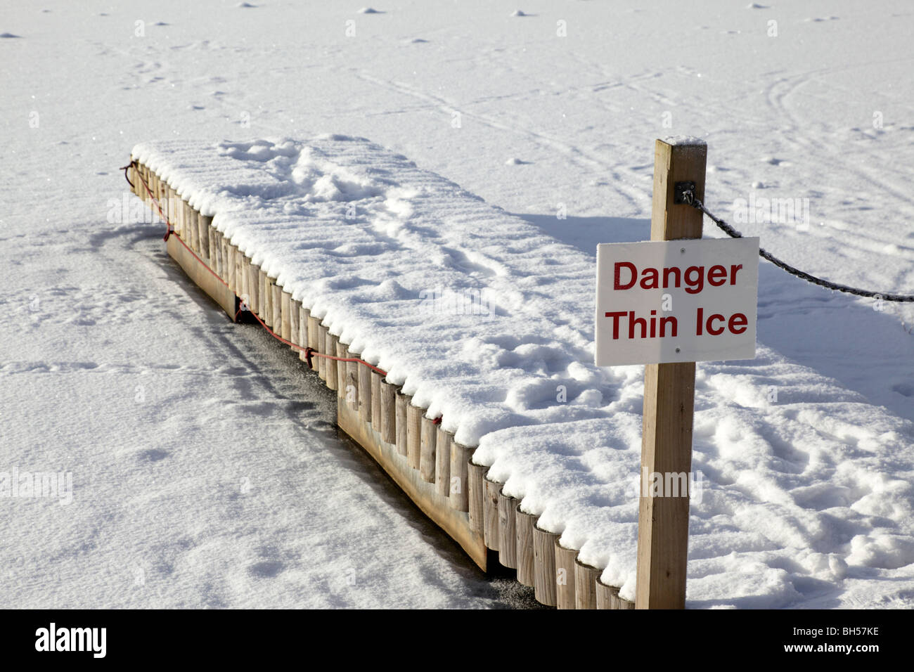 dünnem Eis Gefahrenzeichen auf einem hölzernen Steg führt zu einem zugefrorenen See Center Parcs Penrith uk Stockfoto