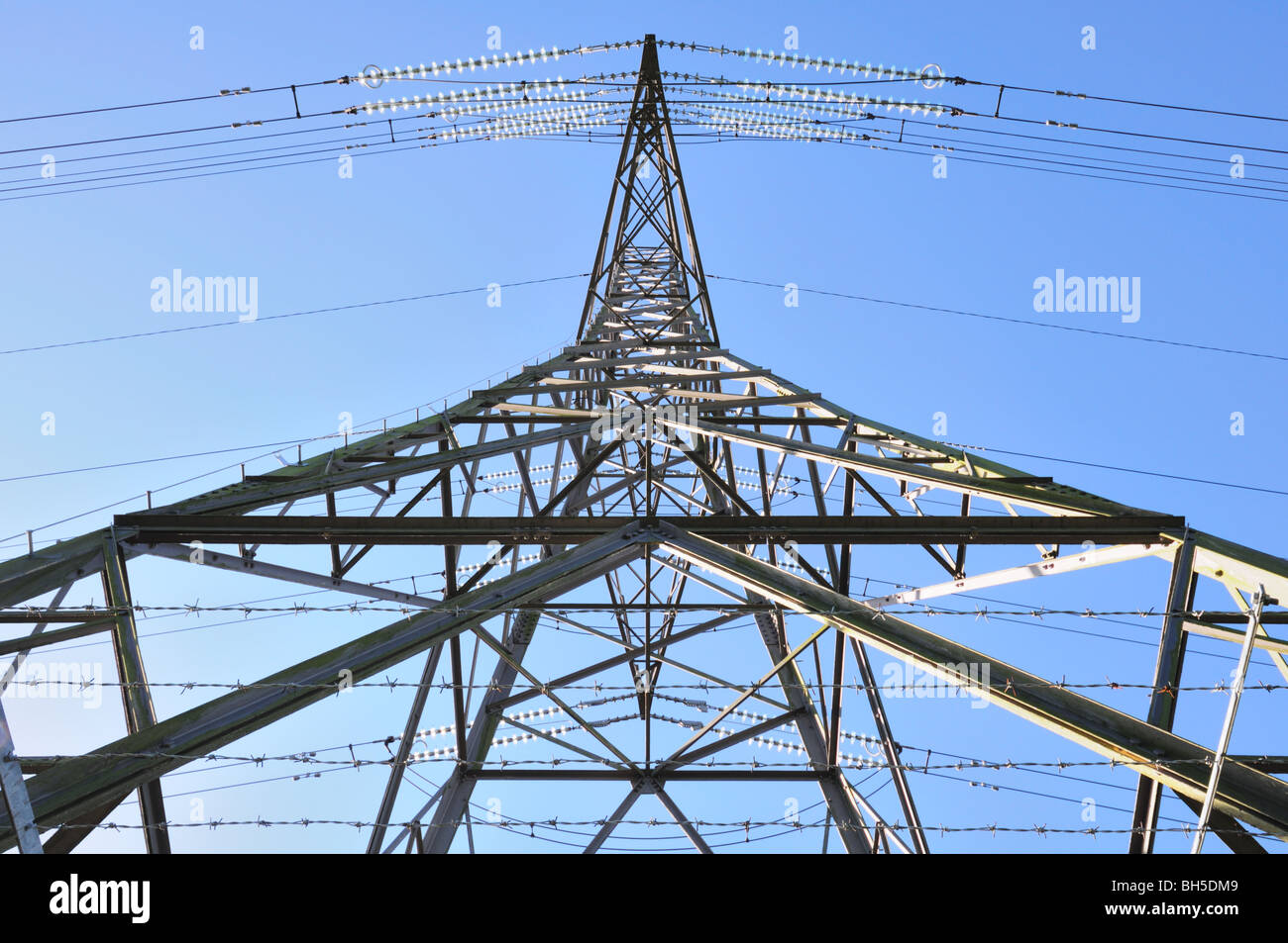 Strommast nach oben von einem ungewöhnlichen Winkel an der Basis mit betrachtet klar blauen Himmel dahinter Stockfoto