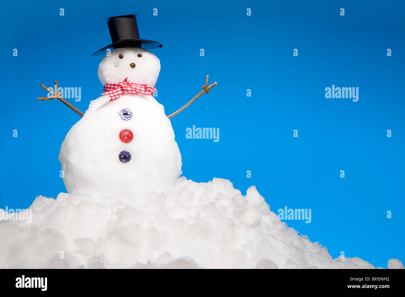 Miniatur-Schneemann auf Schnee mit blauem Himmel hinter Stockfoto