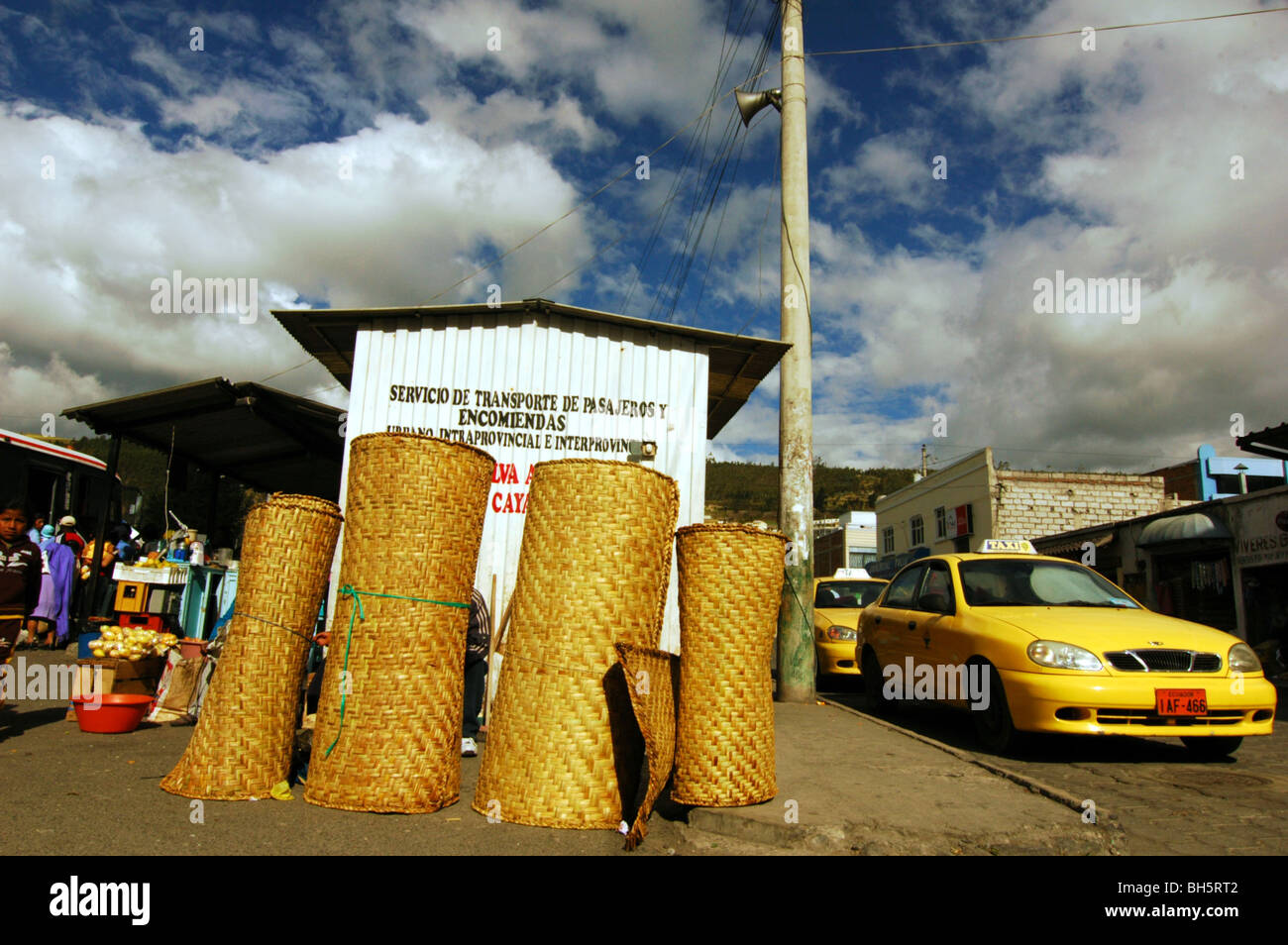 Ecuador, Otavalo, gefaltet Wicker Matratzen in einer Zeile durch ein gelbes  Taxi auf der Straße weiter, eine Bushaltestelle, gegen bewölktem Himmel  Stockfotografie - Alamy
