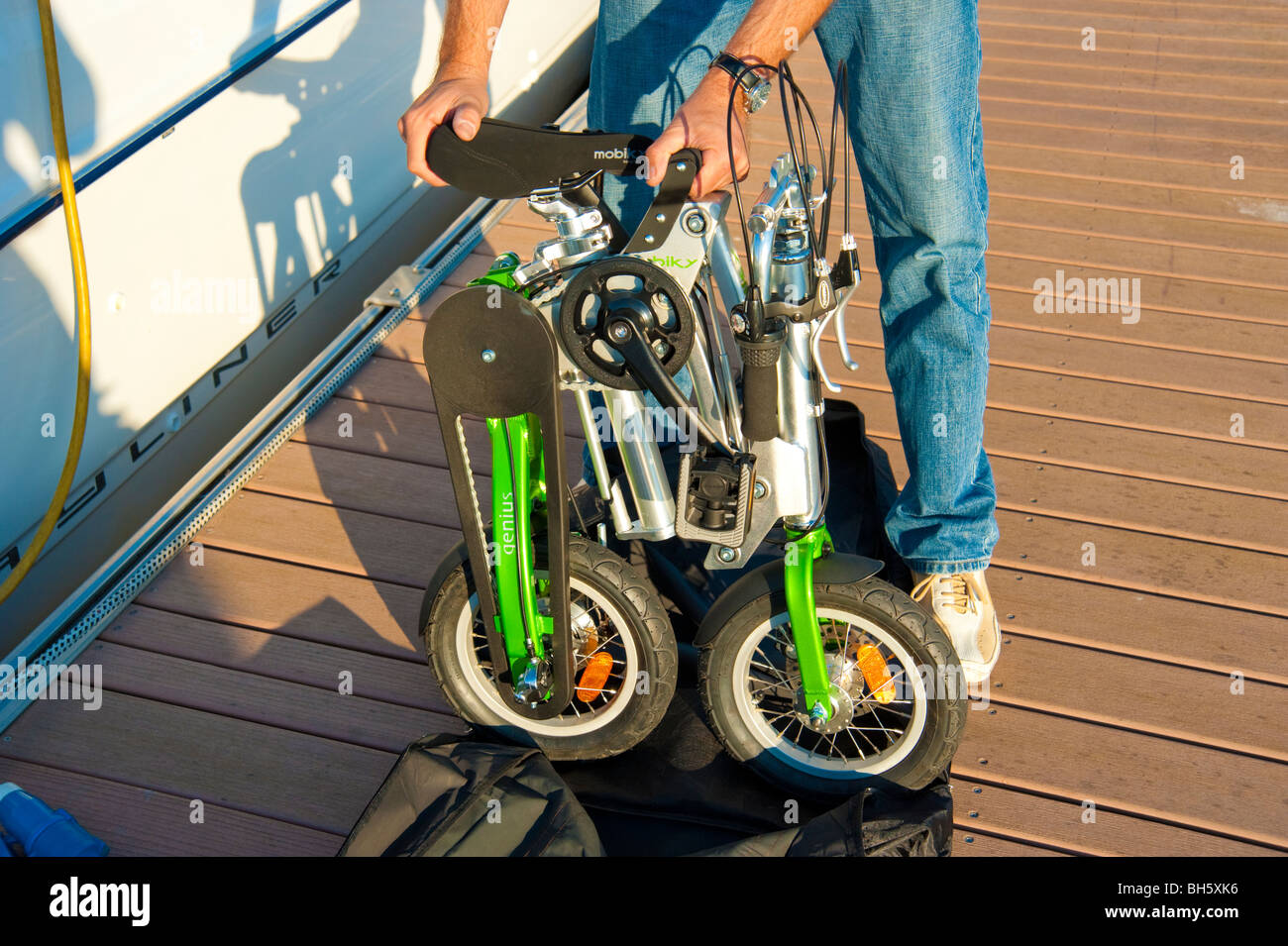 Mann, die Entfaltung einer Mobiky Klapprad auf einem Bootssteg mit Yachten Stockfoto