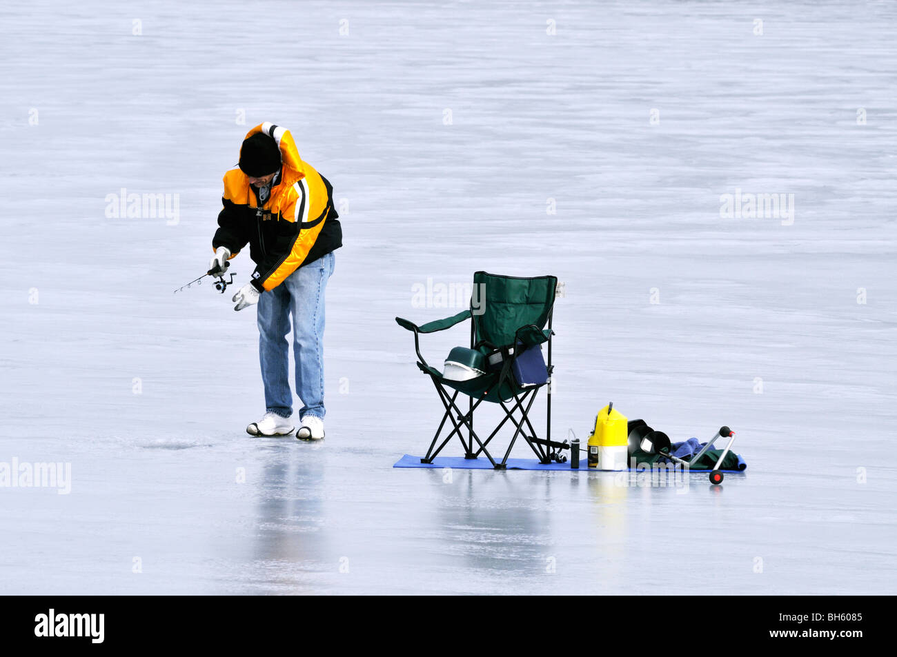Einziger Mann Eisangeln auf zugefrorenen Teich mit Stuhl und Getriebe auf Cape Cod USA Stockfoto