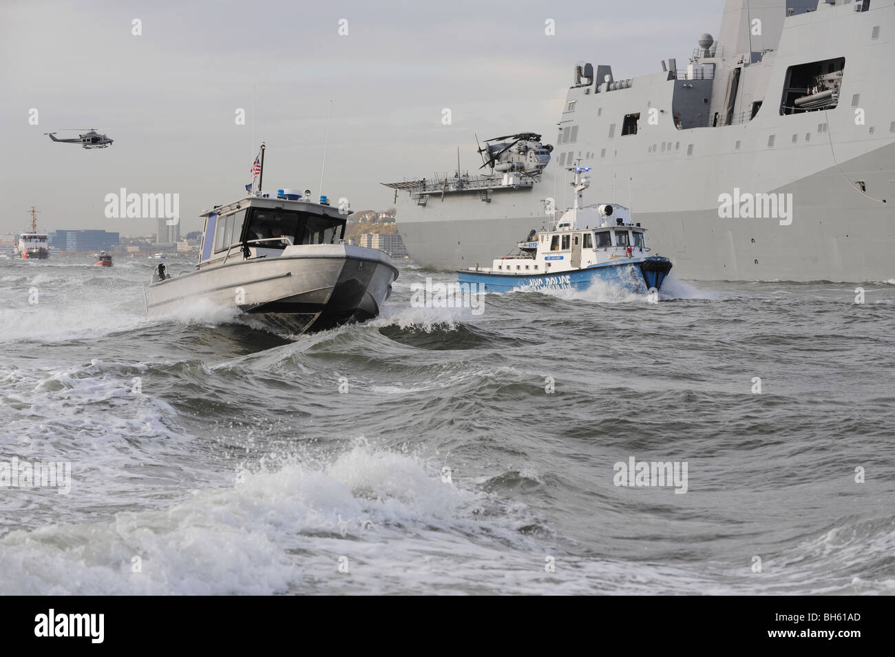 Crews aus der Küstenwache und Polizei Abteilungen escort USS New York, wie es in New York Hafen fährt. Stockfoto