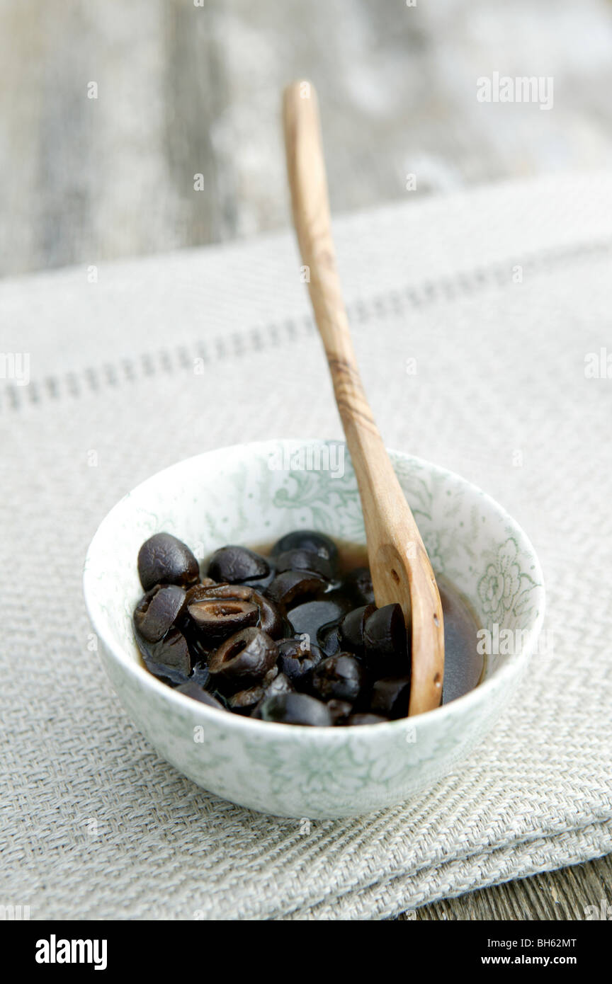 gewürfelte Oliven in kleine weiße Schüssel mit kleinen hölzernen Löffel platziert Stockfoto