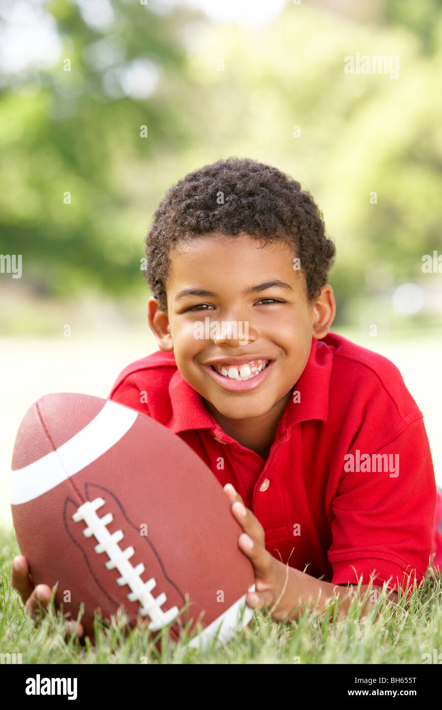 Junge im Park mit American Football Stockfoto