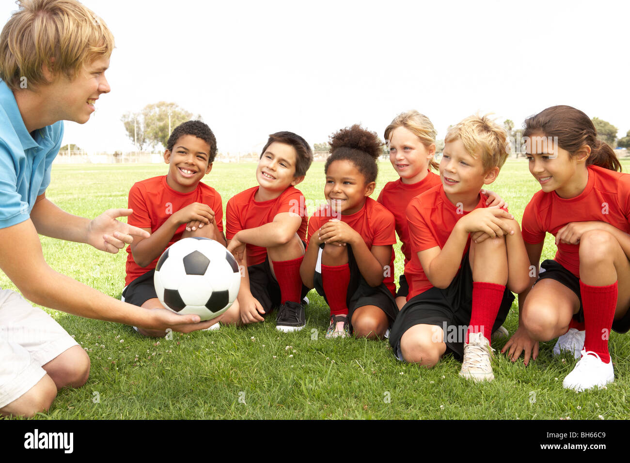 Jungen und Mädchen im Football-Team mit Trainer Stockfoto