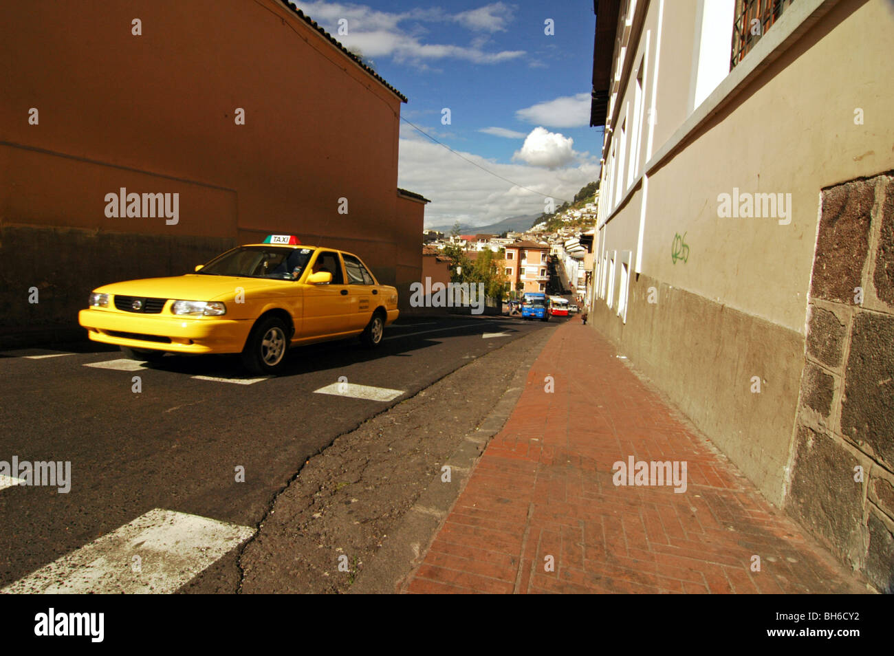 Ecuador, Quito, Yellow Cab auf einer schmalen Straße durch einen Bürgersteig, Stadtbild von Quito in Equador in einem Abstand und Hügel von El Panecill Stockfoto