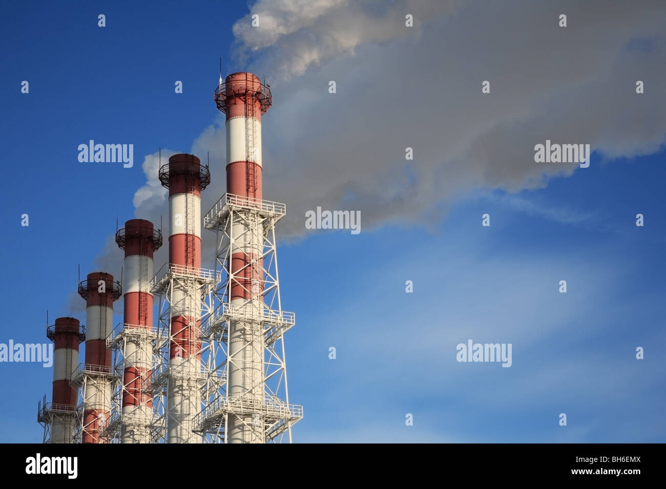 Fünf Schornsteine mit Dampf auf blauen Himmelshintergrund. Stockfoto