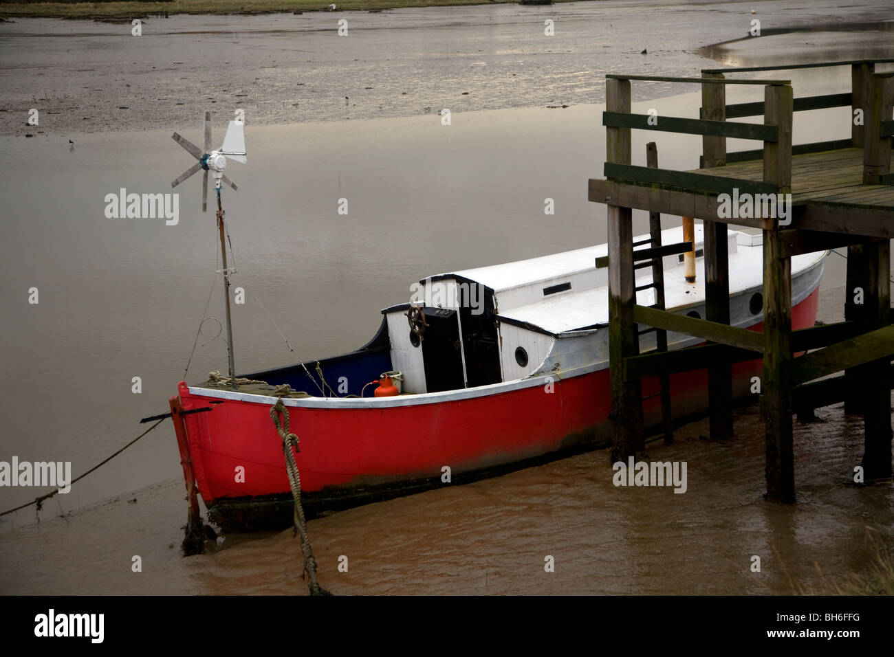 Boot mit roten Rumpf vertäut im Schlamm auf River Deben, Melton, Suffolk, England Stockfoto