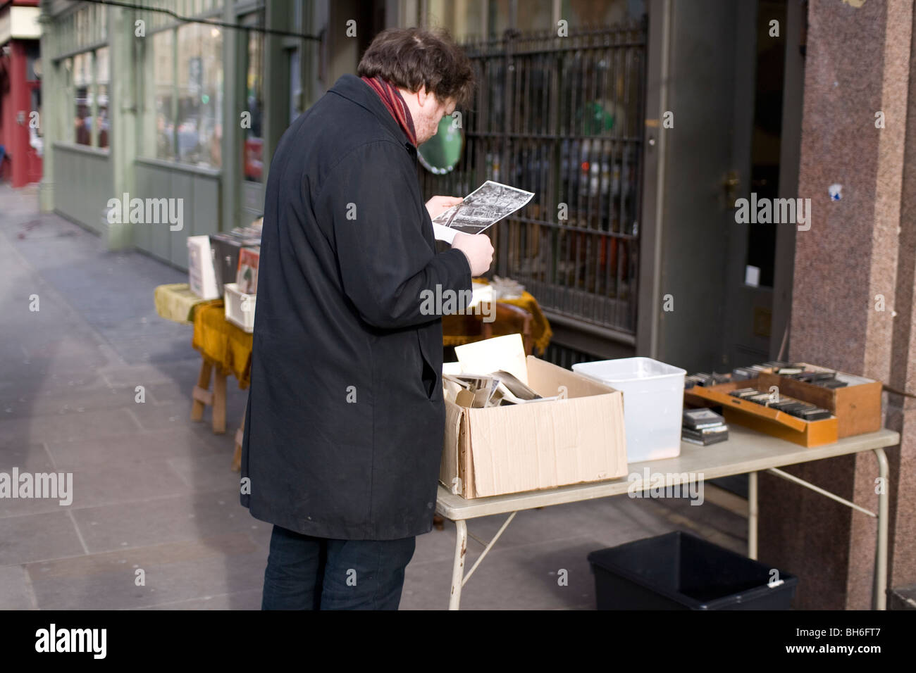 Ein Mann untersucht ein Stück von Ephemera in einem Stall in Londons Commercial St, E1 Stockfoto