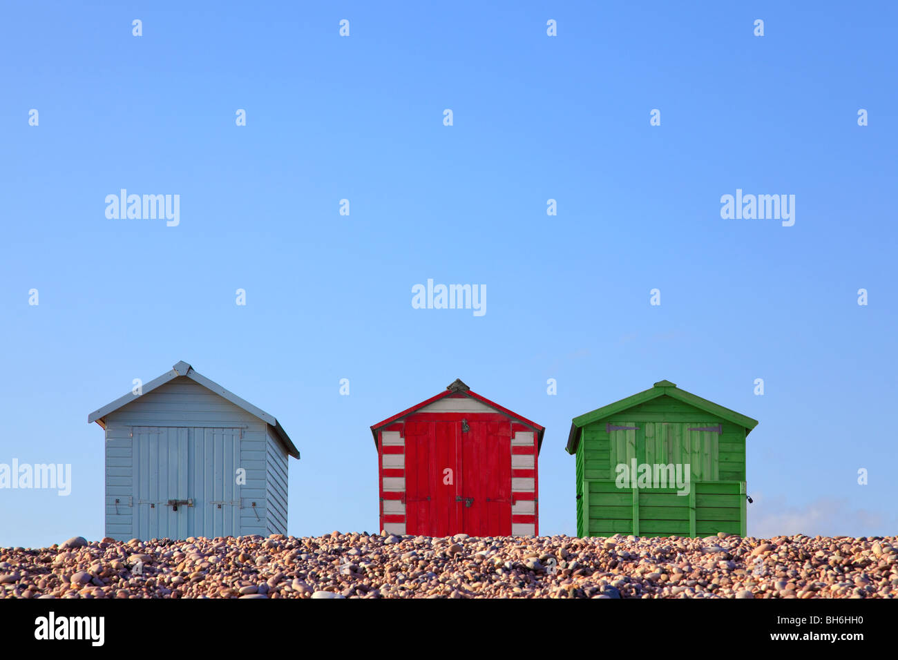 Drei bunte Strandhütten gegen ein strahlend blauer Himmel, gerahmt um textfreiraum im oberen Teil des Bildes zu ermöglichen. Stockfoto