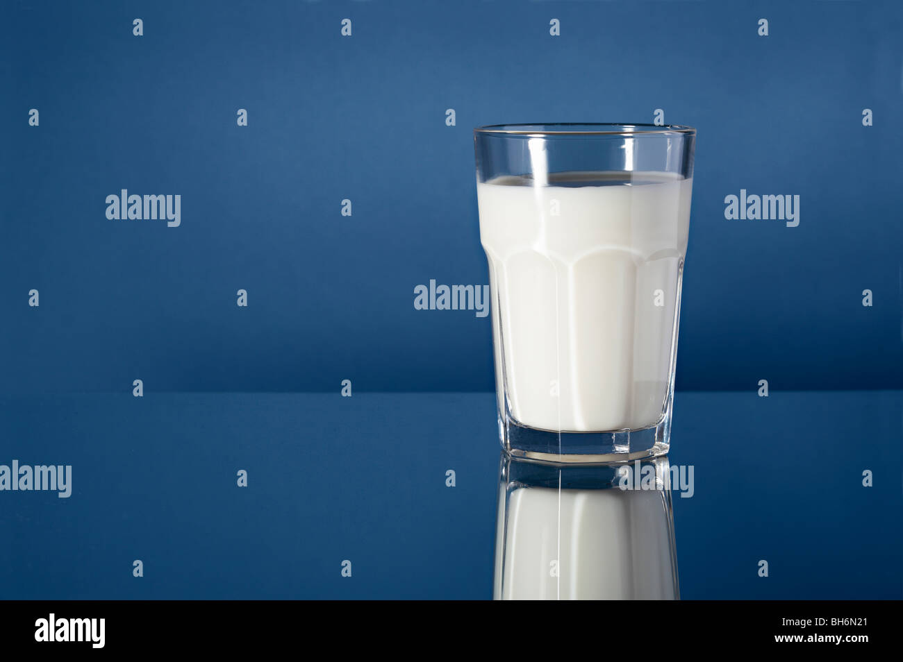 Ein Glas Milch auf reflektierende blauem Hintergrund Stockfoto