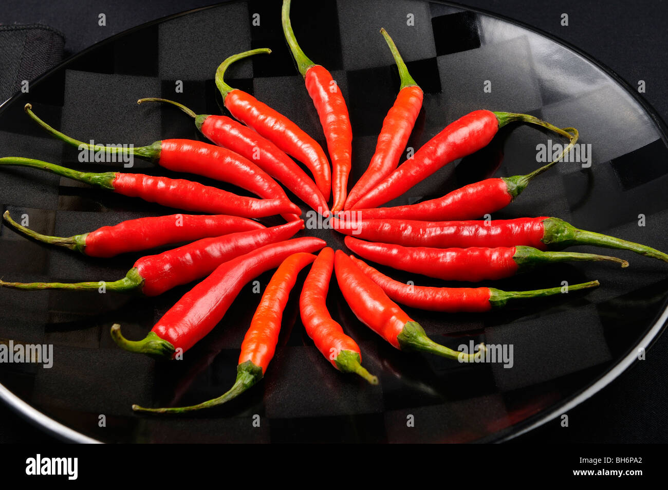 Nahaufnahme von einem Ring von red hot chili peppers auf einer schwarzen Platte Stockfoto
