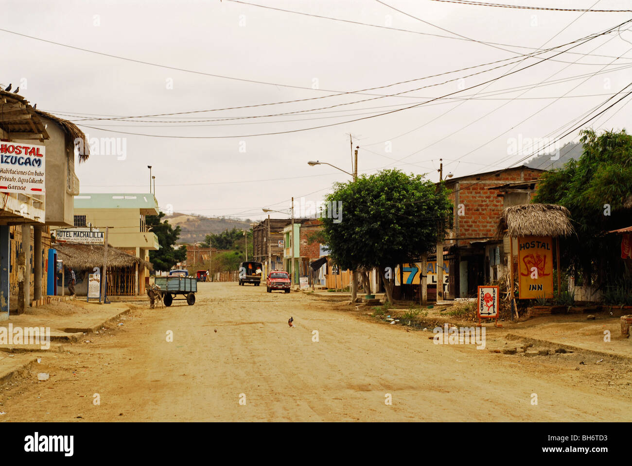 Ecuador, Puerto Lopez, Straßenszene mit einer staubigen Straße und einige hölzerne Läden auf der einen Seite der Straße und andere Häuser o Stockfoto