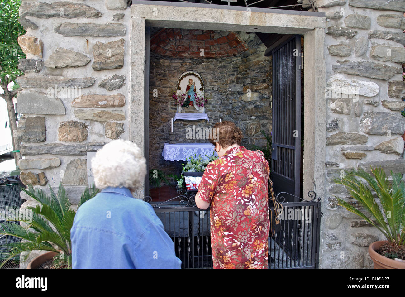 Zwei Frauen Maiking Opfergabe an eine kleine steinerne Kapelle in Vernazza Cinque Terre 5 Länder Italien Italia Stockfoto