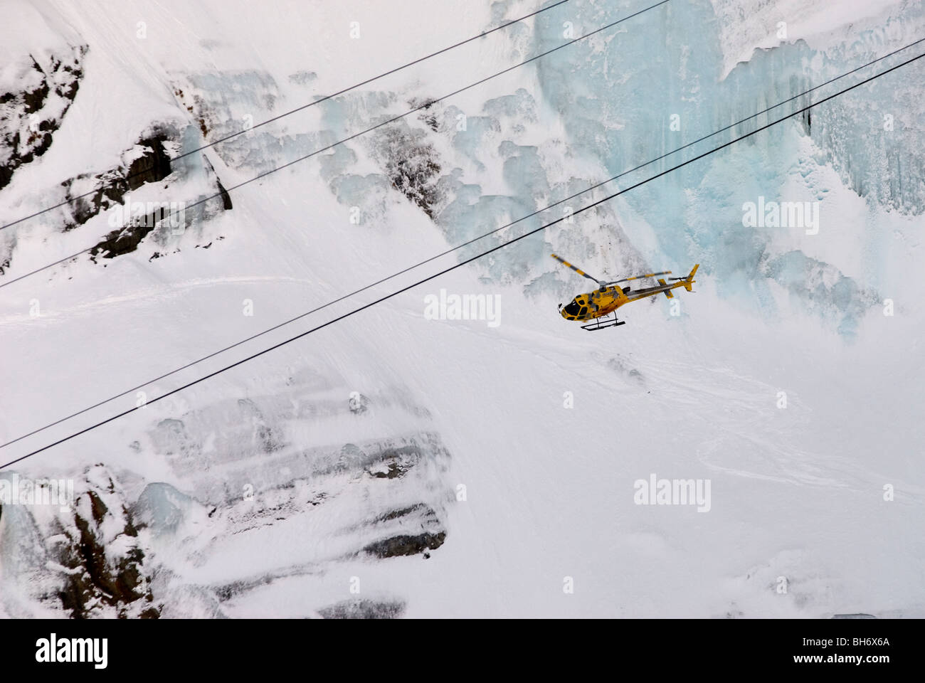 Hubschrauber fliegen vorbei Wand Argentiere Gletscher mit Kabeln von Sessellift Overhead. Stockfoto