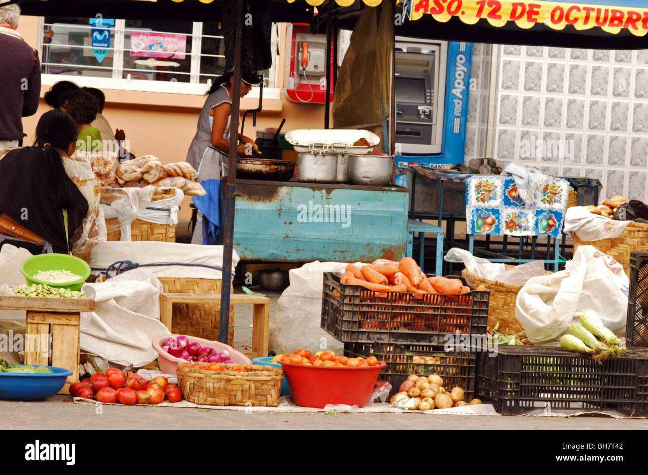 Ecuador, Otavalo, Tomaten, Zwiebeln und Karotten in Töpfe und Körbe auf einem Markt stall mit Frau im Hintergrund Prepaid Stockfoto