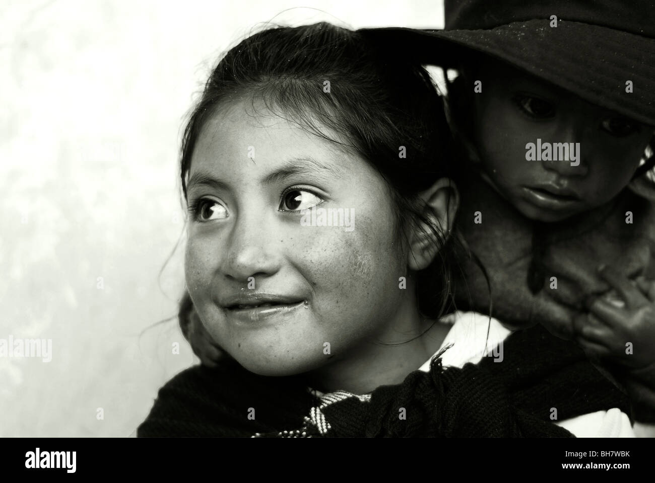 Ecuador, Latacunga, Nahaufnahme von einem Mädchen Ith große helle braune  Augen und Lächeln auf den Lippen, ihre Wangen verbrannt von der Sonne, w /  Babyschwester Stockfotografie - Alamy