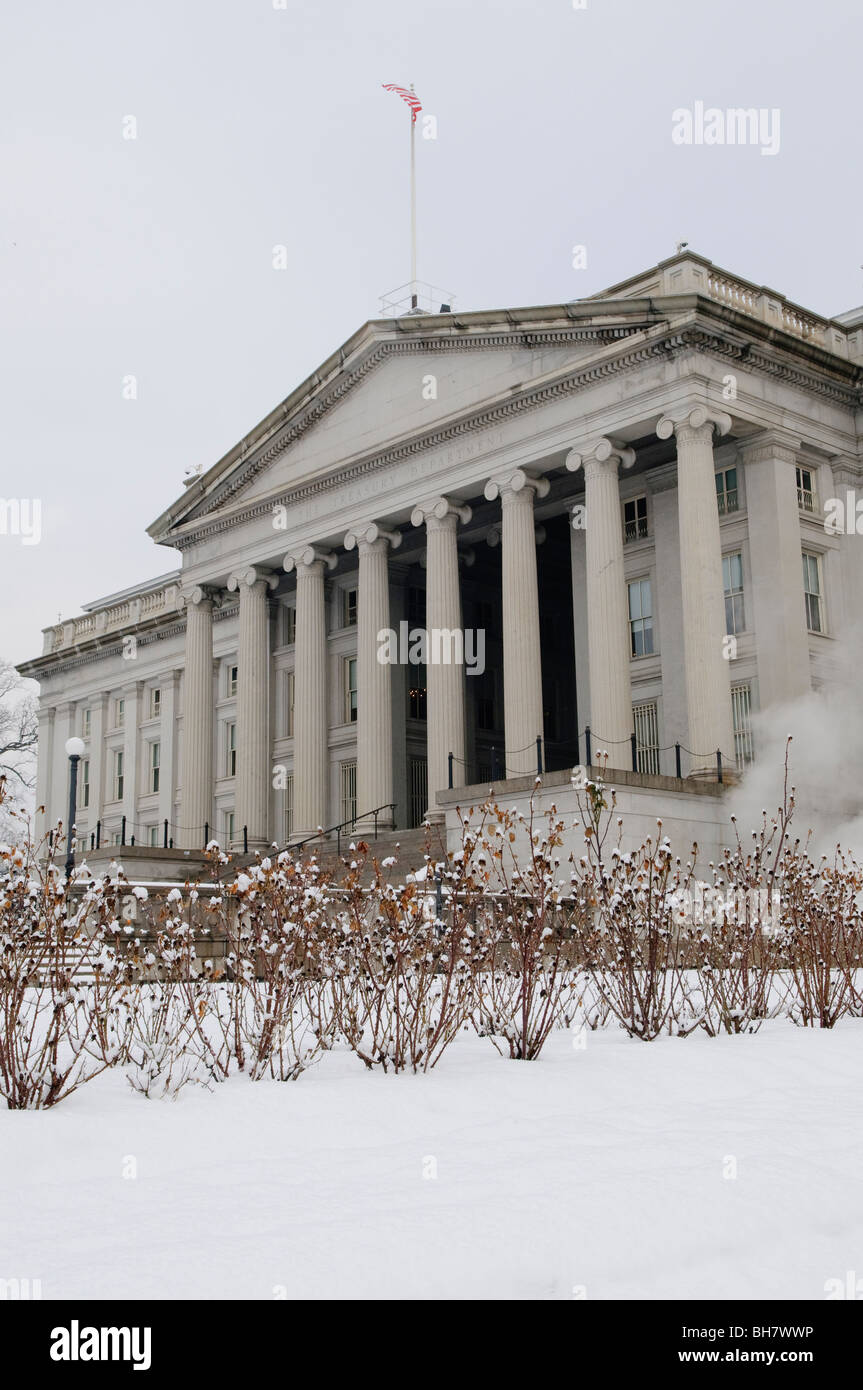 Treasury Building Snow Washington DC // WASHINGTON DC, USA – die Nordfront des Treasury Building in Washington DC, mit einer frischen Schneedecke im Vordergrund. Die ikonische neoklassizistische Architektur hebt sich von der weißen Winterlandschaft ab, in der die amerikanische Flagge über dem Gebäude thront. Stockfoto