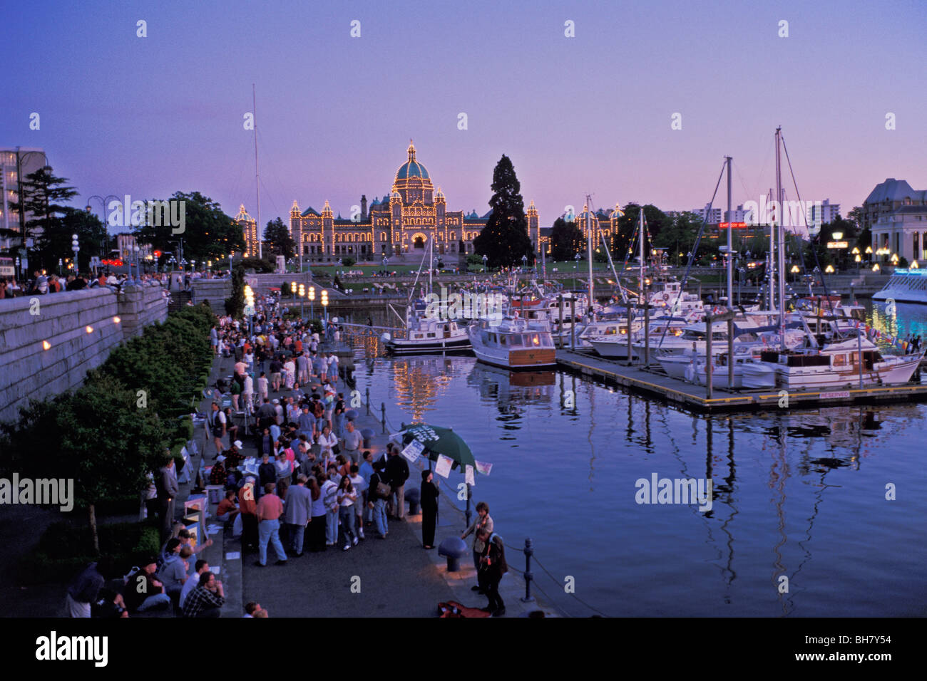 Menschen drängen sich die Esplanade bei Dämmerung, inneren Hafen mit dem kanadischen Parlament Gebäude im Hintergrund, Victoria, BC, Kanada Stockfoto