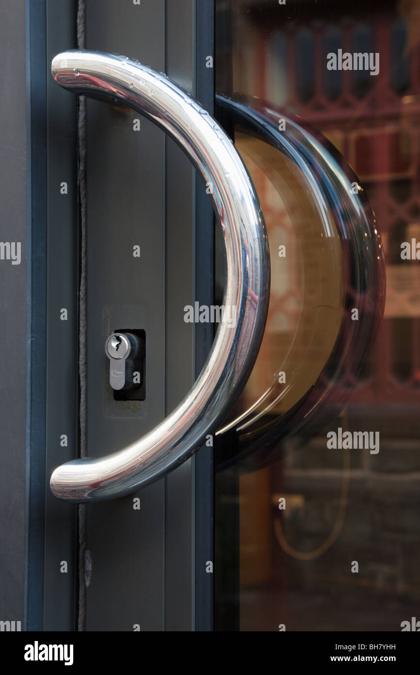 Nahaufnahme einer halbkreisförmigen Chrom Griff und Schlüsselloch auf eine Glastür Stockfoto