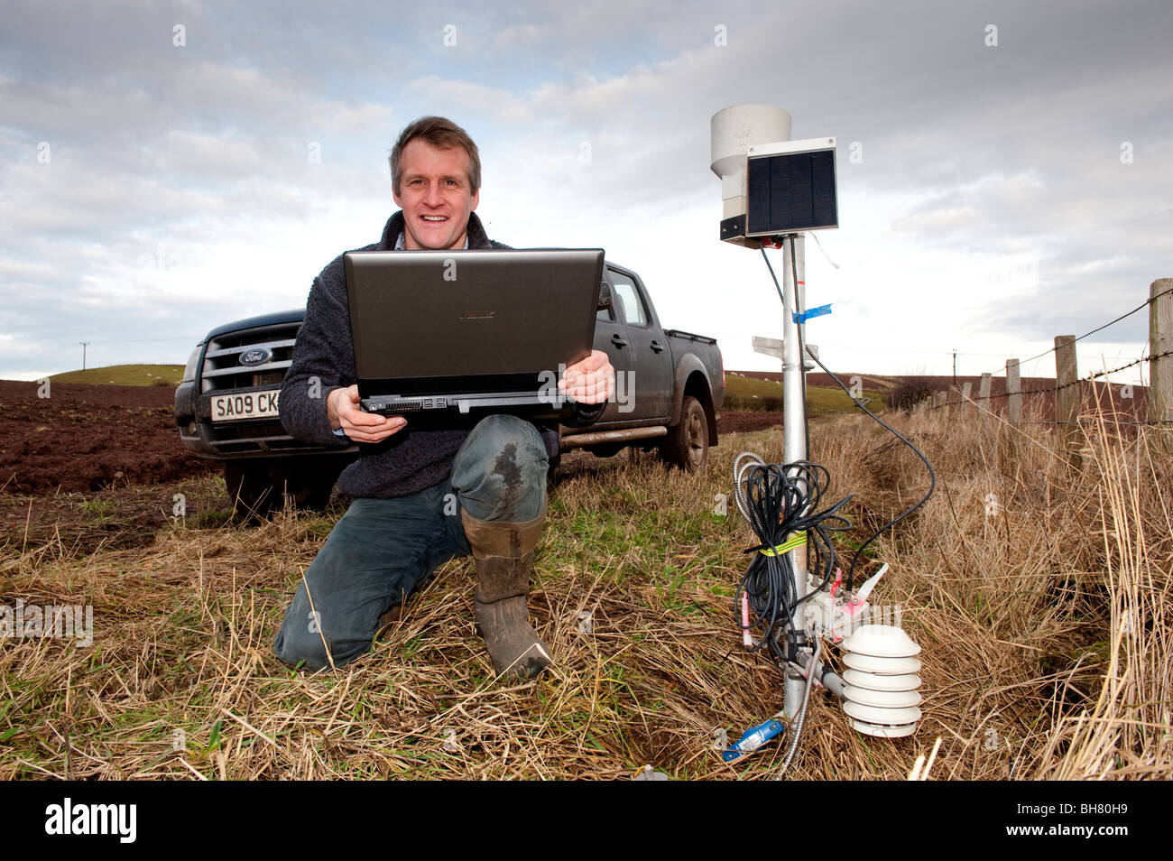 Landwirt Überprüfung elektronischer Wetterstation mit laptop Stockfoto