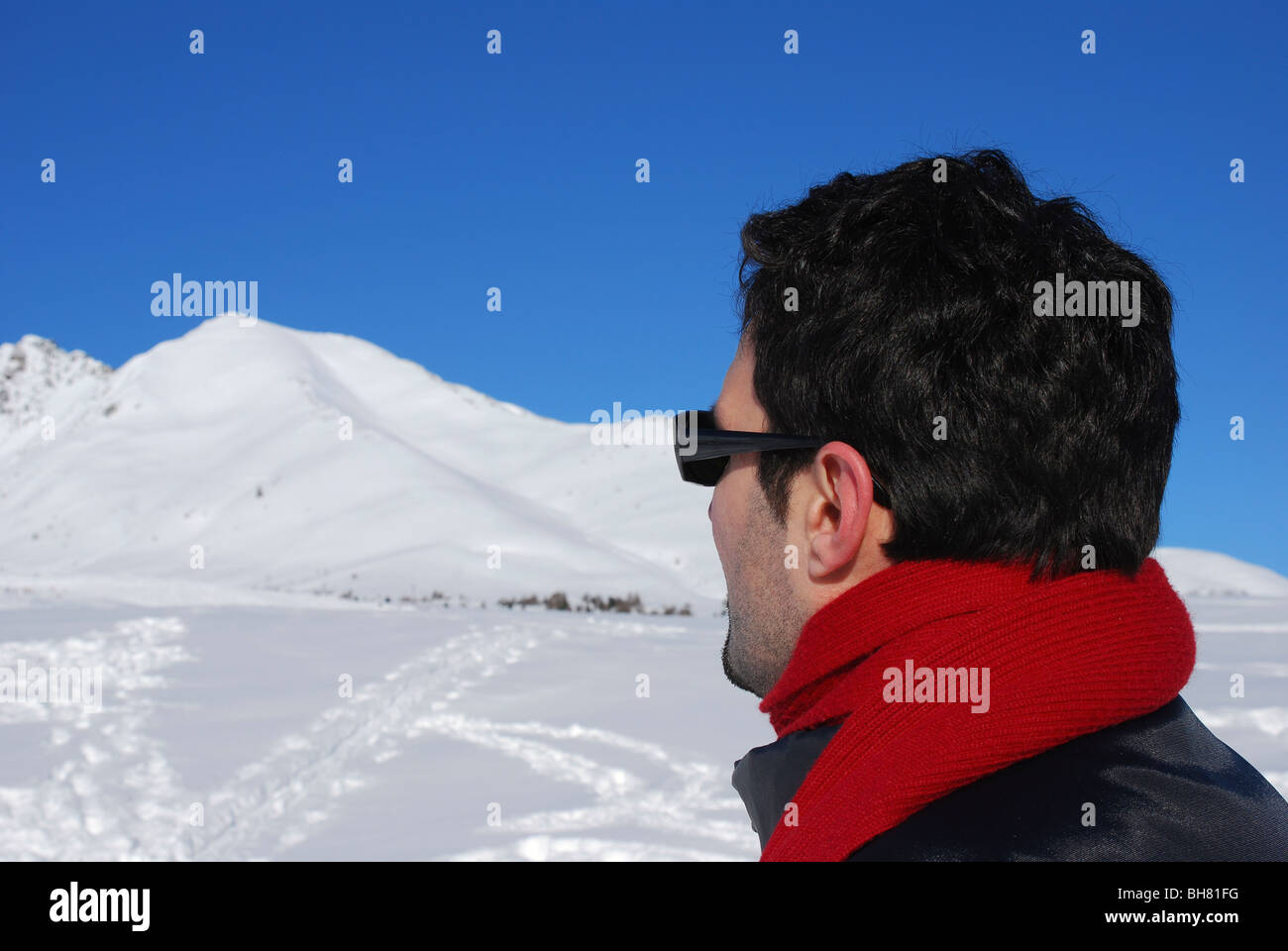 Seitenansicht der Mann mit rotem Schal und Sonnenbrille auf verschneiten Bergen Stockfoto