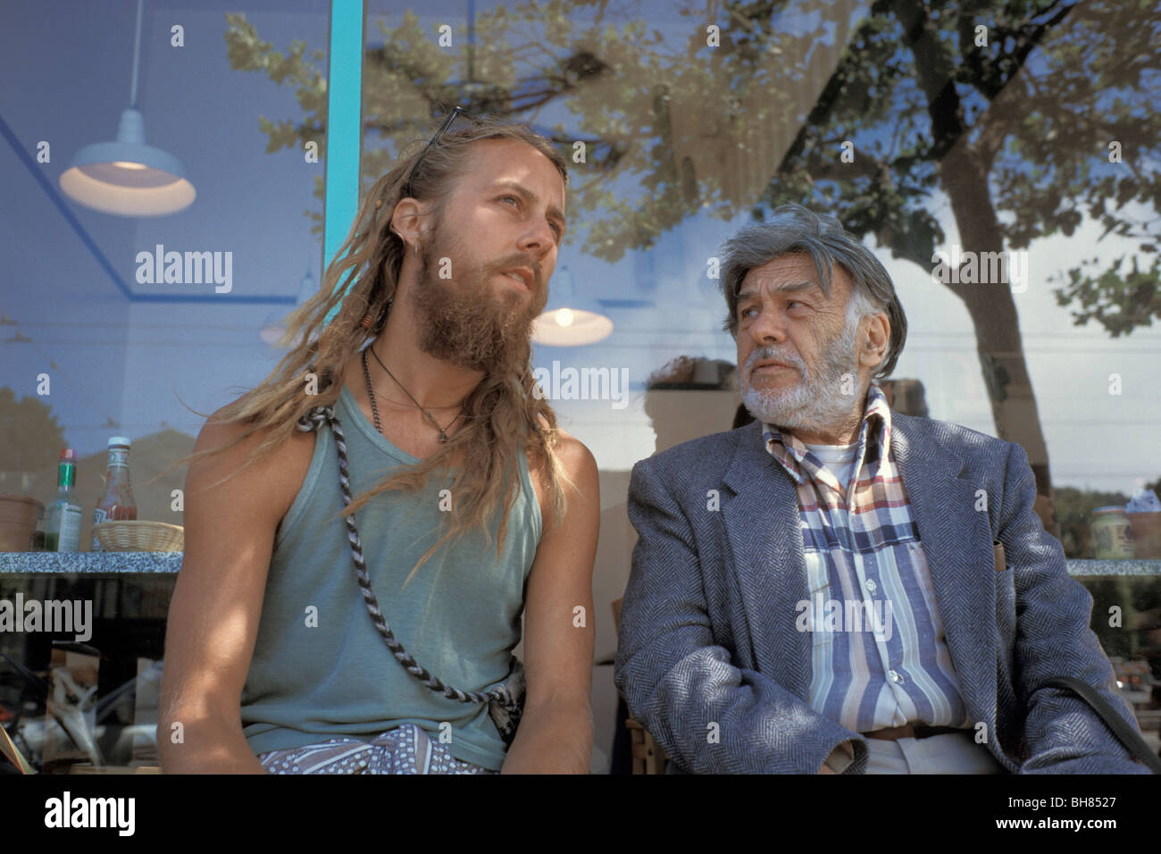 Gegensätze In Aussehen Alter und Kleid, zwei Freunde sitzen auf Bank In Castro District, San Francisco, Kalifornien Stockfoto