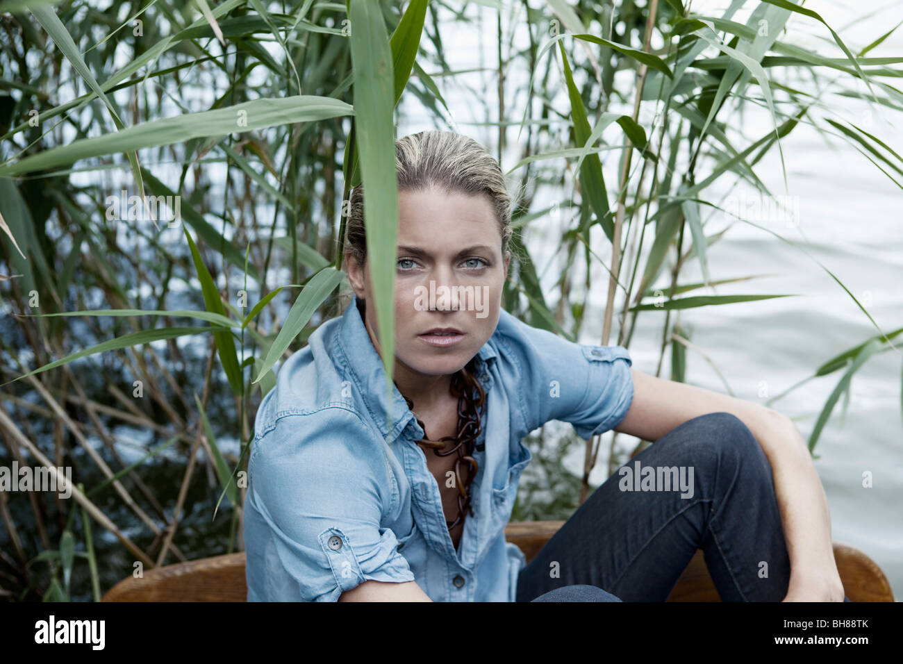 Eine Frau sitzt in der Nähe von Wasser, Porträt Stockfoto