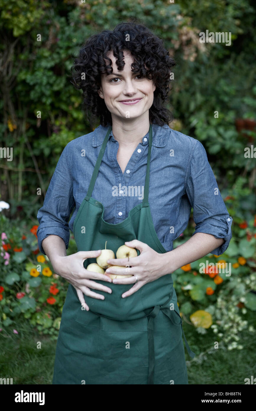 Eine Frau hält eine kleine Gruppe von frisch gepflückten Äpfel in ihrer Schürze Stockfoto