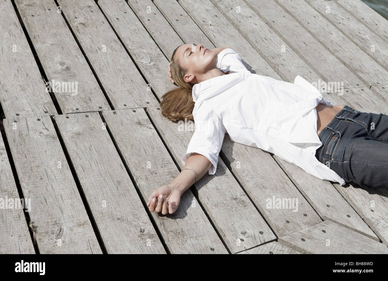 Eine Frau liegt auf einem Holzdeck Stockfoto