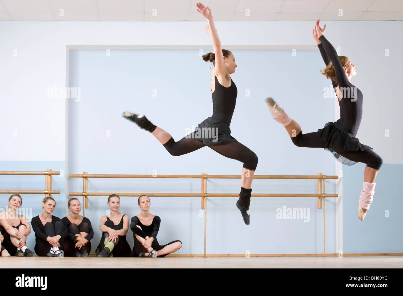 Zwei Tänzerinnen Sprung durch die Luft wie andere schauen auf Stockfoto