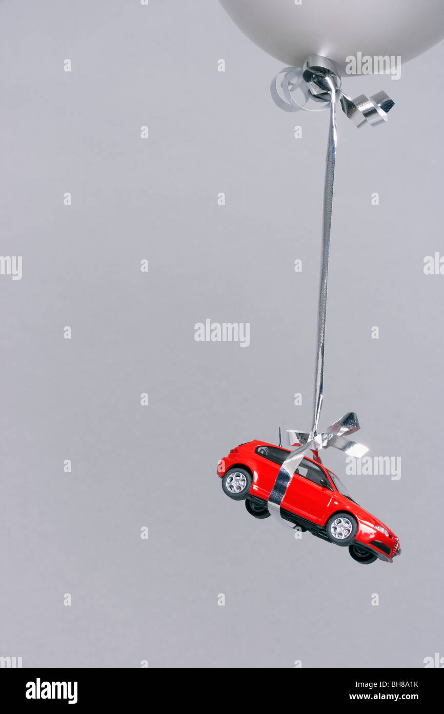 Rotes Auto von einem grauen Ballon durchgeführt Stockfoto