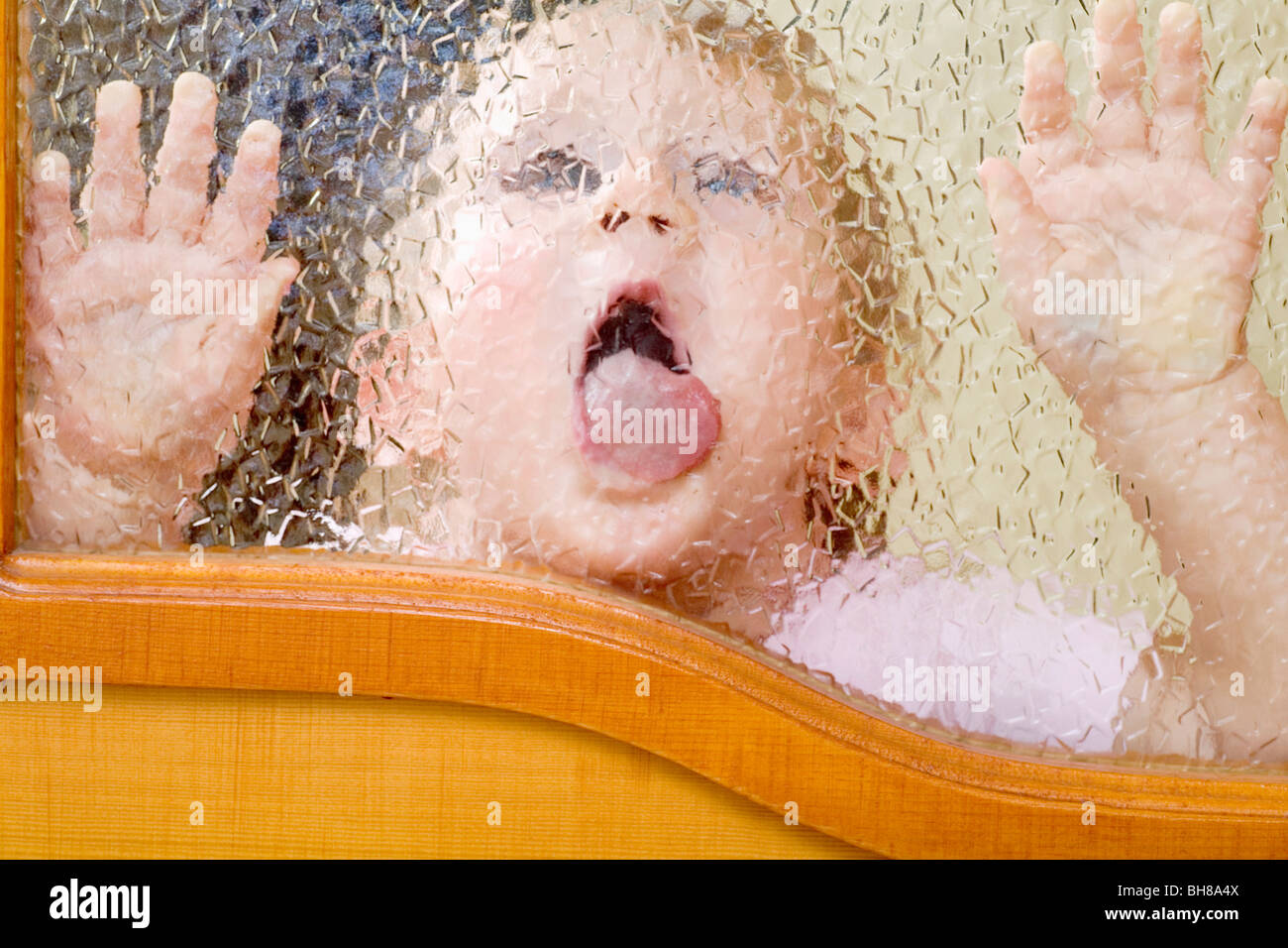 Ein Kind einem abgeschrägten Glasfenster lecken Stockfoto